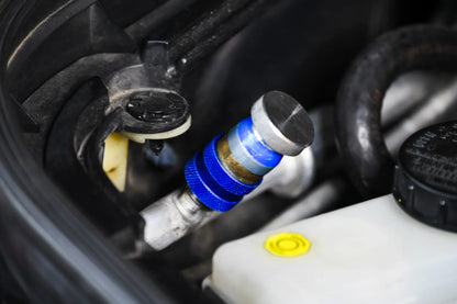 Close-up of car AC service valve with blue cap for refrigerant leak repair