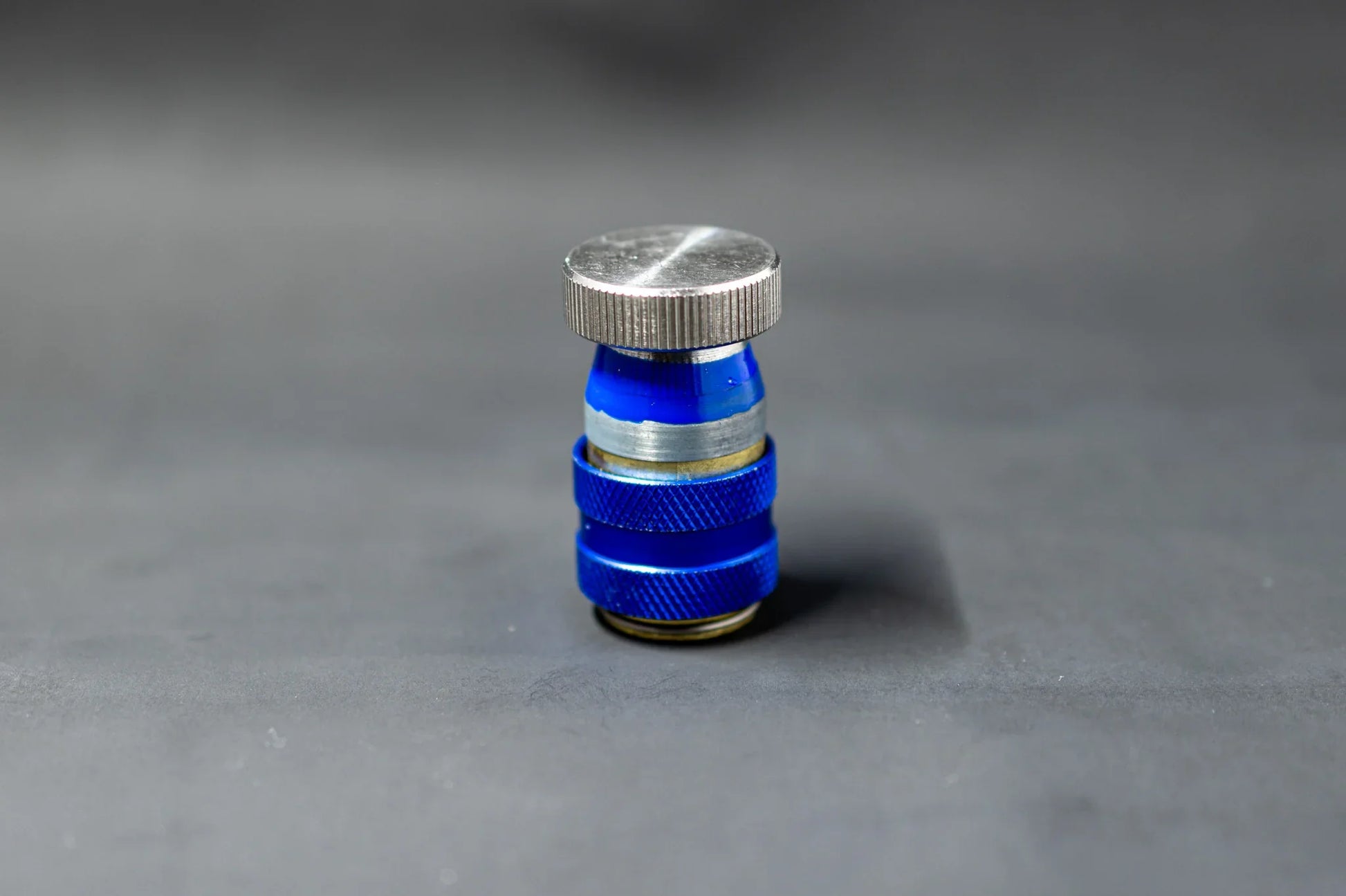 Blue car AC service valve leak repair cap on grey background