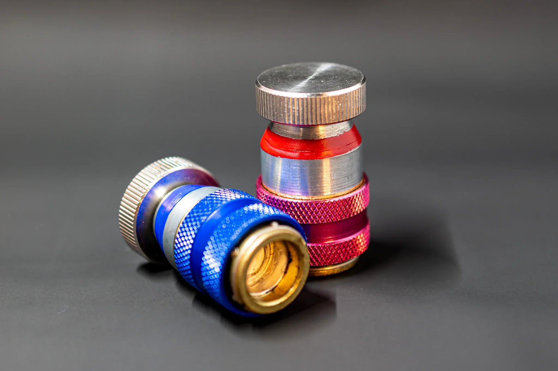 Close-up of blue and red automotive AC refrigerant valve caps on a dark background