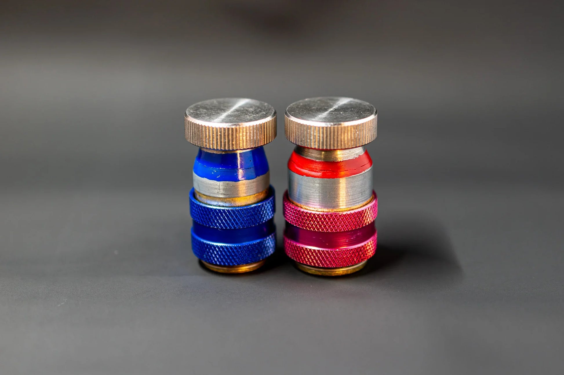 Close-up of blue and red car AC refrigerant service valve caps on a dark background