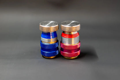Close-up of blue and red car AC refrigerant service valve caps on a dark background
