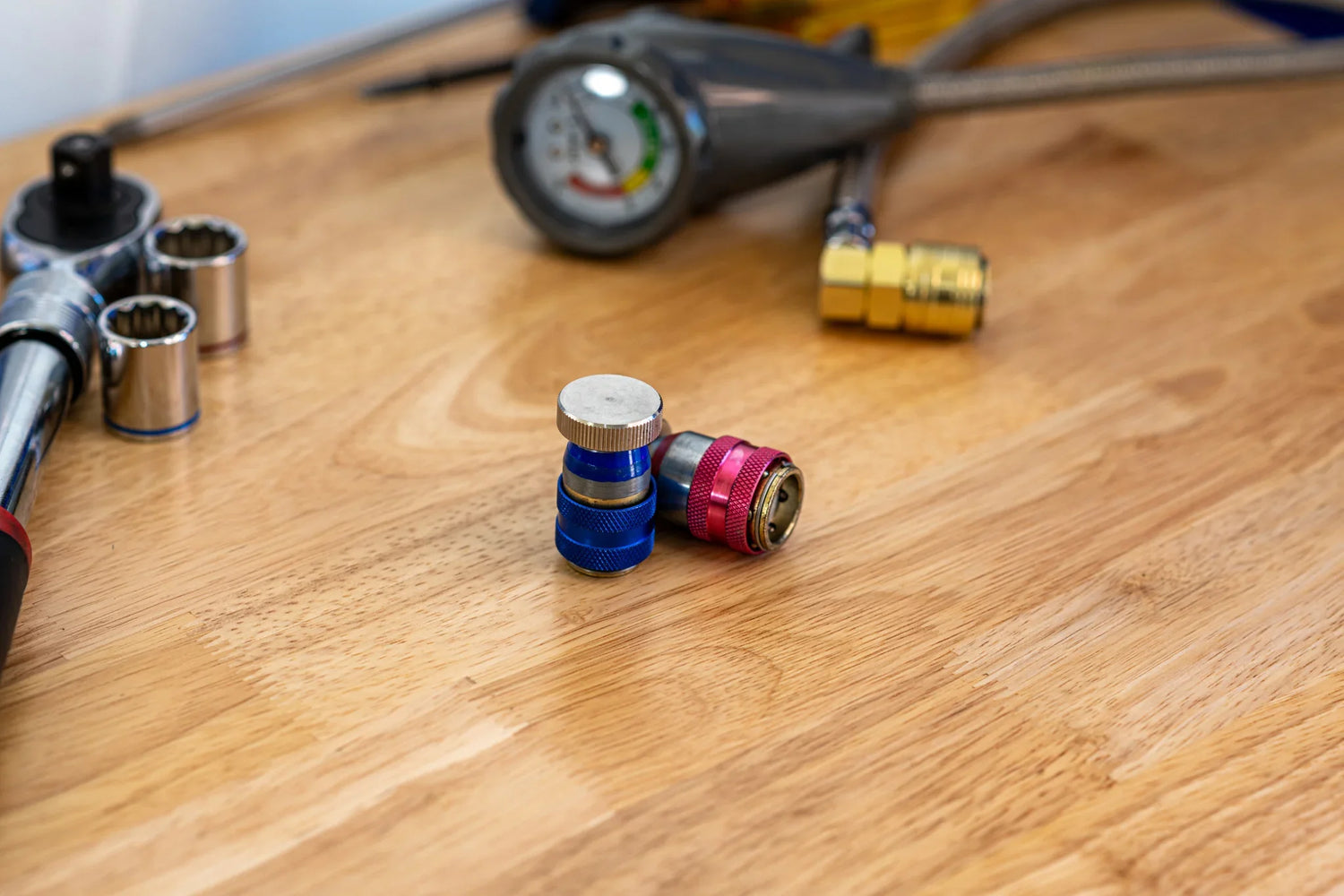 AC service valve tools and gauge on wooden workbench for car AC leak repair