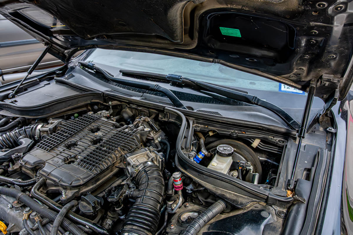 Vehicle under hood with the A/C service port labeled